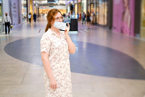 Young woman takes off her medical mask at the mall. End of quarantine and removal of isolation due to coronavirus