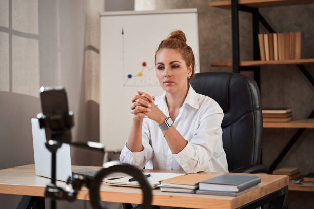 istock Serious teacher sitting at the table during online lesson 1264721287
