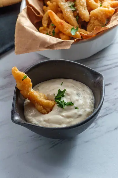 New England fried clam strips served with a bowl of tartar dipping sauce