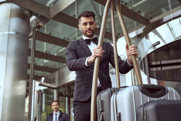 Careful managing of guests luggage is porters main duty Responsible doorman wearing presentable uniform moving a luggage trolley while delivering guests bags safely bellhop stock pictures, royalty-free photos & images