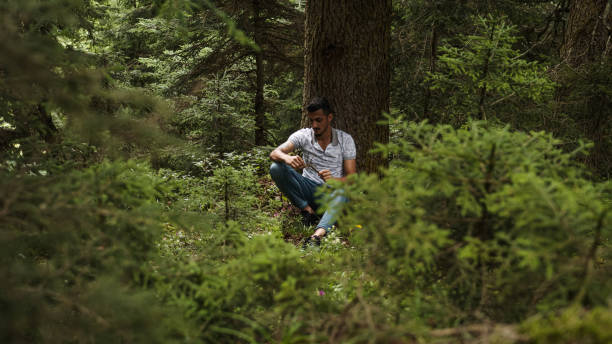 istock Handsome young man leaning on tree is dealing with wood stick in his hand , relaxation concept 1264725162