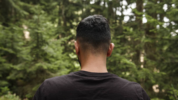 istock Young man wearing a black t-shirt, walking through the forest, back view 1264726008