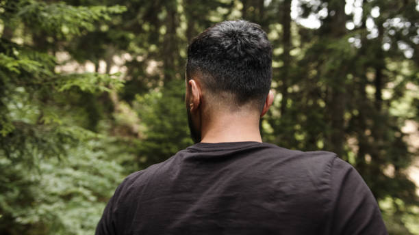istock Man wearing a black t-shirt, walking through the forest, back view 1264726053