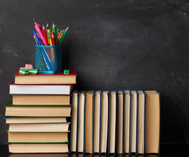 istock stack of various books, stationery on black chalk board background, back to school 1264728408