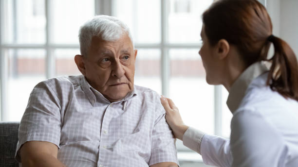 ärztin tröstet verärgert ältere patientin bei treffen - aging process middle women men stock-fotos und bilder