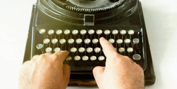 Writing using an old typewriter Male hands writing a text by typing the keys of an old typewriter. Vintage items and old mechanical technology typewriter writing retro revival work tool stock pictures, royalty-free photos & images