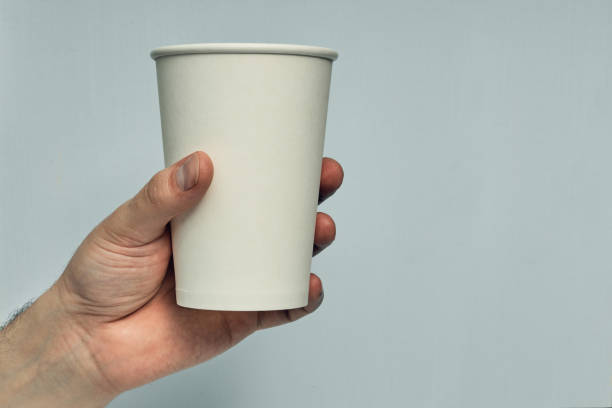 istock Paper cup in hand on a colored background. Eco-friendly materials in a coffee shop, biodegradable disposable tableware. Close up 1264736577