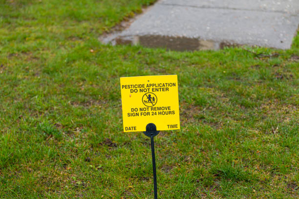 Pesticide application warning sign on lawn A small yellow sign is placed on the front lawn agter chemical pesticide was applied as a warning to do not enter. apply fertilizer stock pictures, royalty-free photos & images