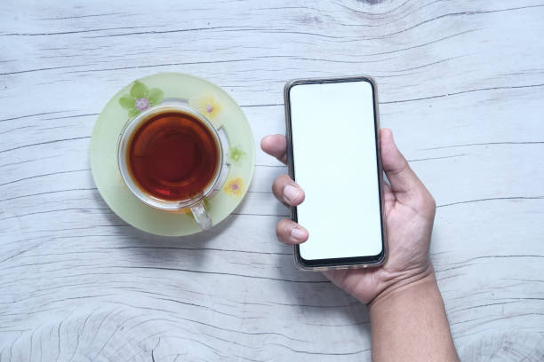 istock Top view of man hand holding smart phone with empty screen on table 1264763330