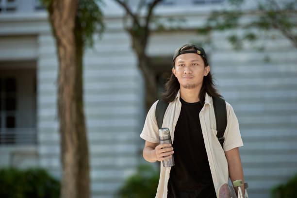 istock Asian male skateboarder walk to office 1264763872