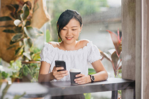 istock Young asian woman using smart phone in a cafe 1264769409