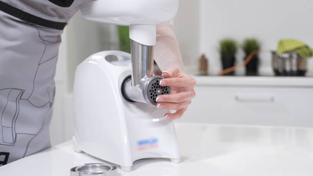 istock Female hands assembles meat grinder head for providing quality mince from meat. Electric mincer machine for minced meat per minute, make sausages, mashed berries, squeeze juice. Dolly shot 1264769586