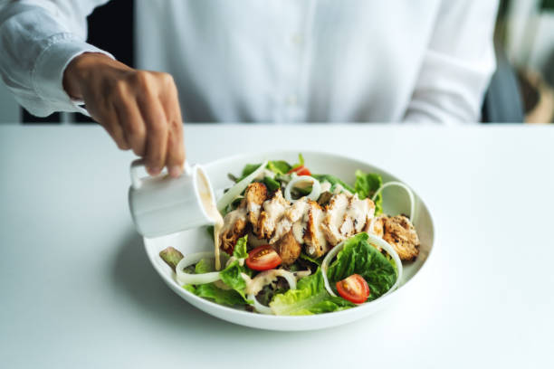 istock a woman pouring dressing into a chicken salad 1264769604