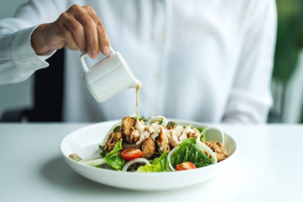 una donna che versa condimento in un'insalata di pollo - condimento per insalata foto e immagini stock