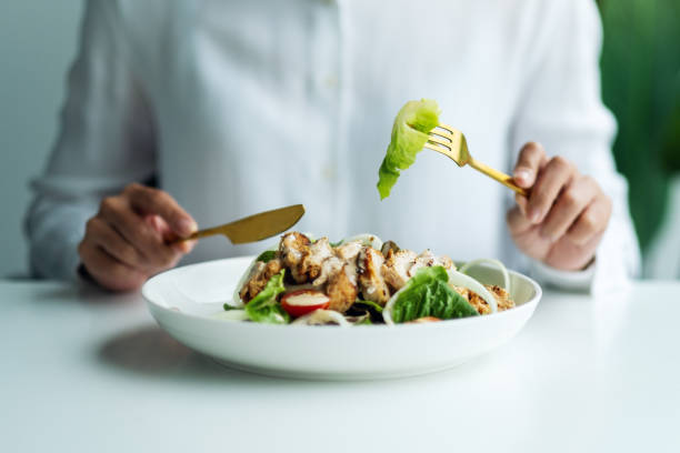 a woman eating chicken salad on table in the restaurant stock photo