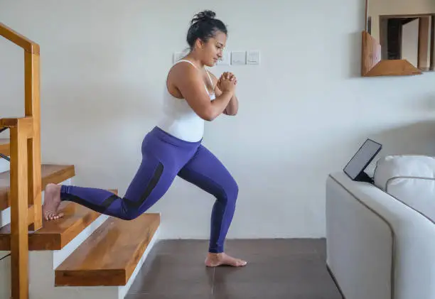 Portrait shot of an Asian woman doing lower body exercise in the stairs of her home
