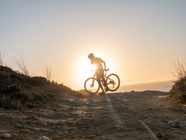 istock Mountain biker riding on the edge of a cliff at sunset 1264784947