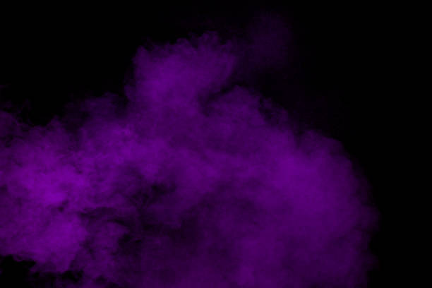 Purple dust particles explosion on black background. Color powder dust splashing.