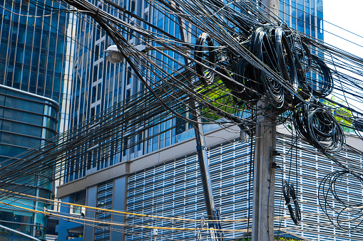 Post with electrical wiring in Thailand. Coils of wires