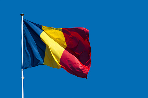 Close-up on the flag of Romania waving atop of its pole.