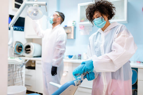 istock Female dentist assistant preparing dentist's chair for a patient visit 1264795897