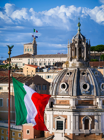 Rome, Italy -- The Italian tricolor flag flies over the Altare della Patria or Vittoriano, the Italian national monument built in the historic center of Rome on the northern slope of the Campidoglio (the Roman Capitol Hill) and Piazza Venezia between 1885 and 1935 in honor of the first King of Italy, Vittorio Emanuele II. On the horizon the Italian flag on the Quirinal Palace (Italian Presidential House). Image in High Definition format.