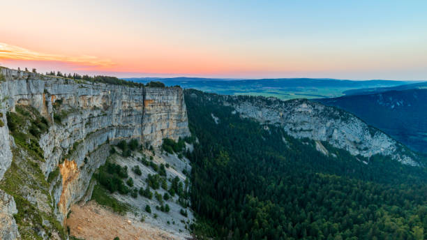 brilho colorido após o pôr do sol com nuvens com vista para o creux du van canyon. rostos rochosos íngremes nas montanhas jura. paraíso para caminhantes e amantes da natureza - jura canton - fotografias e filmes do acervo