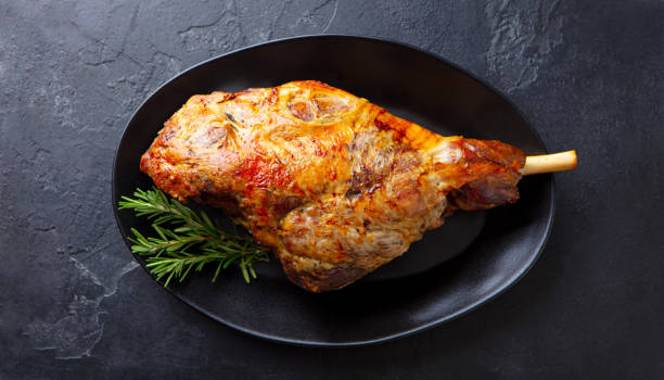 istock Roasted lamb leg on a plate. Black background. Close up. Top view. 1264799804