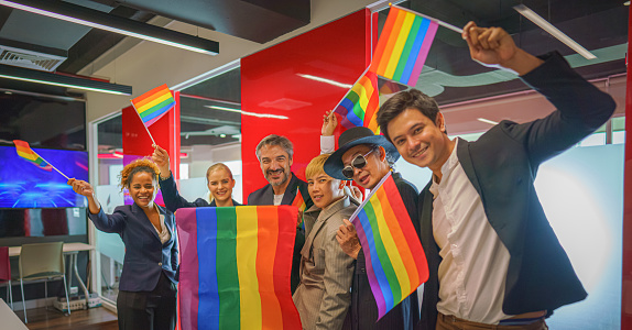 grupo diverso de personas de negocios (hombre, mujer, gay, transgénero, lesbiana, asiática, caucásica, afroamericana, lgbtq) con la bandera arco iris a mano se combinan como trabajo en equipo en la oficina, selectivo enfocado photo