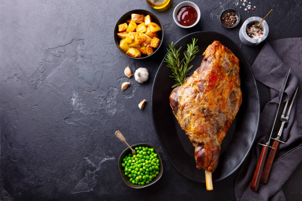 istock Roasted lamb leg with potato and green peas. Black background. Copy space. Top view. 1264803287