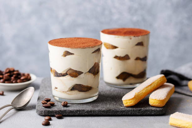 deser tiramisu w szkle na desce do krojenia. szare tło. z bliska. - tiramisu dessert italian culture spoon zdjęcia i obrazy z banku zdjęć