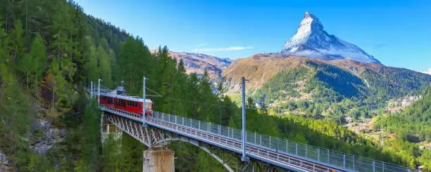 Zermatt, Switzerland. Gornergrat red tourist train on the bridge and Matterhorn peak banner panorama in Swiss Alps