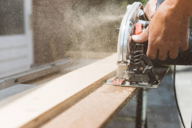 Carpenter using circular power saw for cutting wood, home improvement, do it yourself (DIY) and construction works concept, action shot stock photo