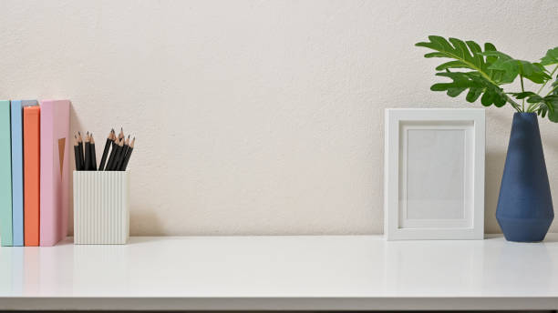 istock Modern decor of workspace with books, pencils, frame and vase on white background. Front view. 1264812274