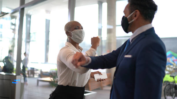 Business people on a safety greeting for covid-19 on office's lobby - with face mask Business people on a safety greeting for covid-19 on office's lobby - with face mask alternative lifestyle photos stock pictures, royalty-free photos & images