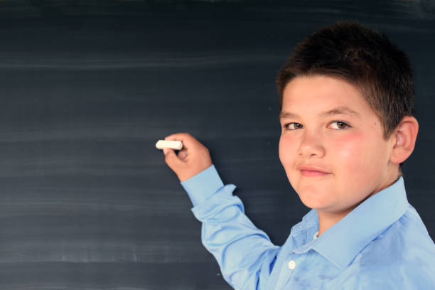 istock School student boy posing at the clean blackboard, 1264813290
