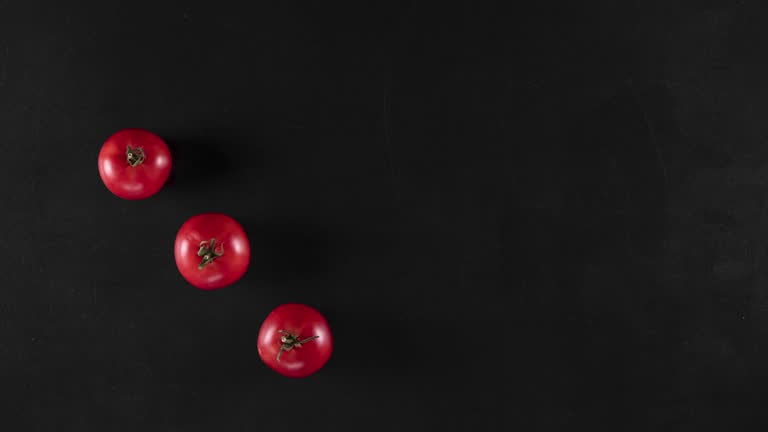 stop motion animation with red tomatoes and handwritten text on a black chalkboard, top view. Concept of vegetarian food or advertisement with vegetables