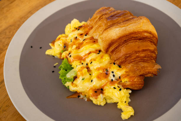 istock Hot breakfast croissant with egg on grey plate. Wooden table background 1264815257
