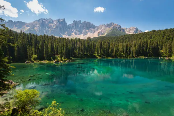 Scenic view of picturesque Carezza Lake - Lago di Carezza - Karersee with reflections of fir woods and mountains in famous crystal clear turquoise water Mount Latemar, Dolomites, South Tyrol, Italy