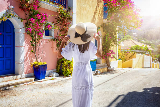 A woman in a white summer dress walks down the streets of the village Assos, Kefalonia A tourist woman in a white summer dress walks down the colorful streets of the little village Assos on the island of Kefalonia, Greece kefalonia stock pictures, royalty-free photos & images