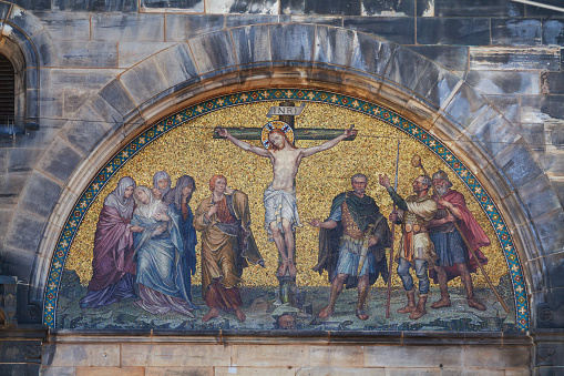 Christ at cross of Golgotha: wonderful mosaic above main Portal of cathedral Dom of Bremen. Cathedral is eldest church in Bremen from middle ages, several times modified and in 19th century restored with great effort. Master builder was in 19th century Max Salzmann. Works were made between 1888 and 1901. It one shows Jesu at cross to Golgotha and his suffering. Mosaic is made of Venetian Murano mosaic.