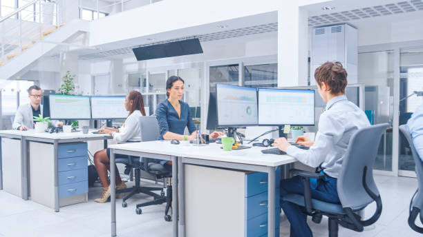 istock In the Big Busy Corporate Office Female Manager Using Desktop Computer, Around Her Businesspeople and Experts Working with Clients, Having Discussions and Analysing Statistics 1264819482