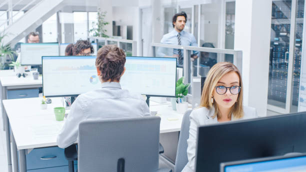 istock In the Bright Busy Office Rows of Diverse Professionals Working on Desktop Computers, Doing Client Support, Communicating with Customers, Monitoring Statistics. 1264819486