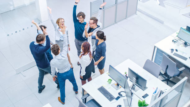 istock Eight Successful Office Workers doing Team Building Exercise Stacking Hands Together in the Unifying Spirit of Creativity and Common Cause. High Angle Shot in Modern Bright Office Building 1264819516