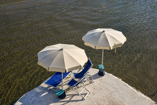 Elevated view of deck chairs and parasols on the water's edge in summer, Liguria, Italy