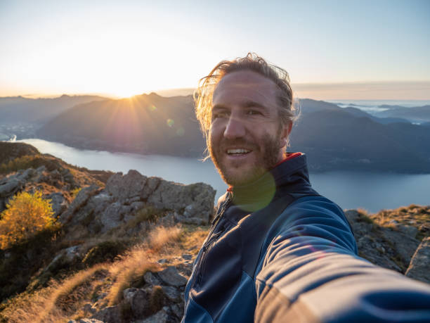 istock Young man on mountain top takes selfie at sunrise 1264823947