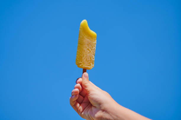 istock hand of a child with a yellow popsicle against deep blue sky 1264824285