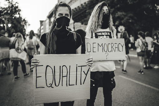 Two young women protesters holding placards with text 