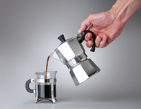 Man's hand holding and pouring italian coffee into a Glass cup