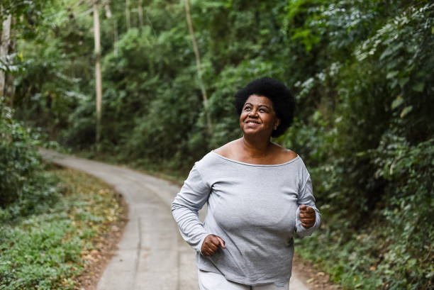 donna che corre nel parco naturale - running jogging african descent nature foto e immagini stock